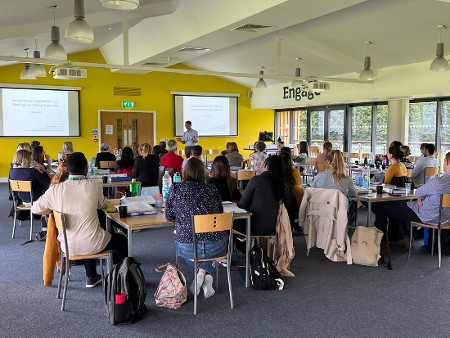 Image of people sitting at tables and listening to a lecturer - attending one of the short course