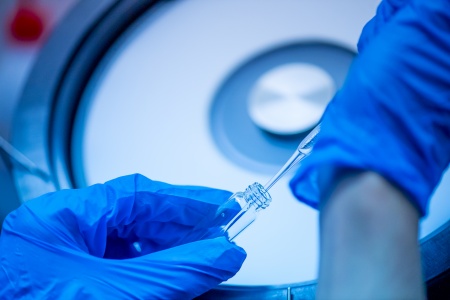 Person wearing blue latex gloves and holding a pipette inside a test tube